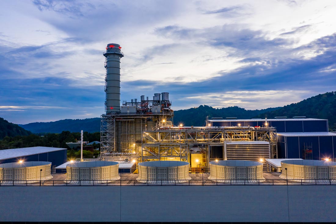 Power plant operations – looking west across cooling tower to HRSG, pipe rack, and turbine building